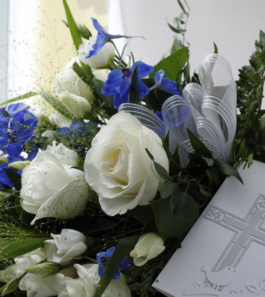 Blumenarrangement mit weißen Rosen und blauen Blüten, kombiniert mit einer tiefen Karte mit gekreuztem Motiv.